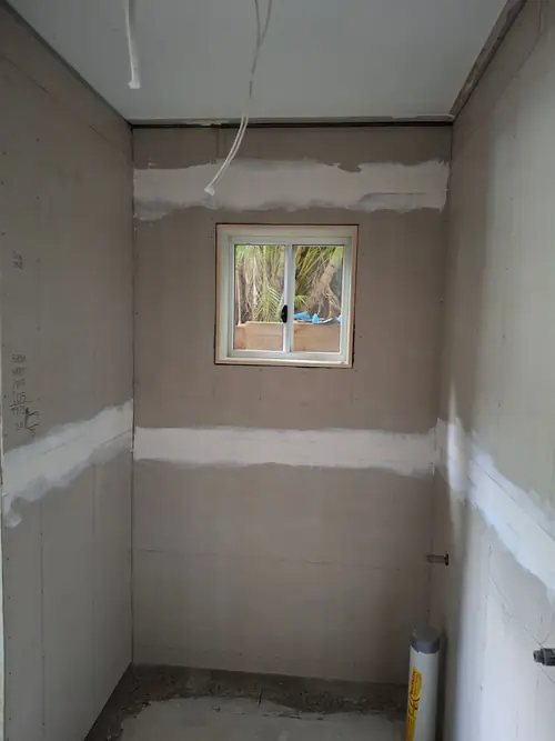 Creation of a new bathroom in the existing structure . The wall has been cut and reframed to install a window . The walls have been straightened , framed and the villaboard.